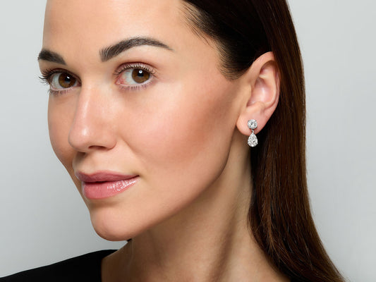 Model wearing platinum diamond drop earrings with pear shaped drops