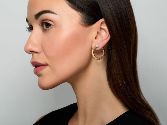 Woman wearing an 18k gold tubogas hoop earring with diamond top