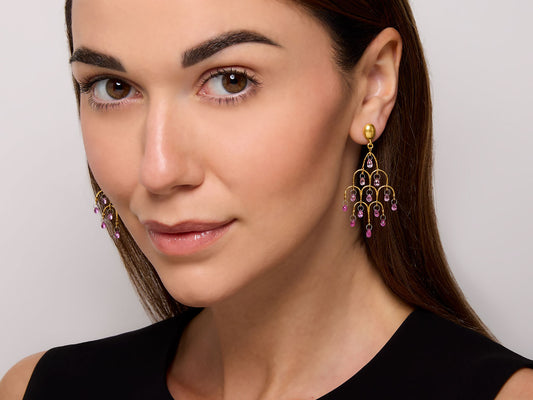 Model wearing gold chandelier earrings with pink sapphires