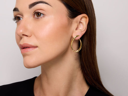 Woman wearing a polished 18K gold loop earring