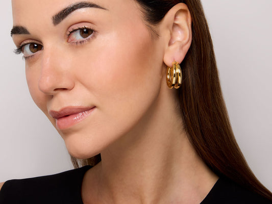Model wearing polished 18K yellow gold double hoop earrings