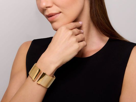 Woman wearing a wide polished 18K gold tubogas cuff
