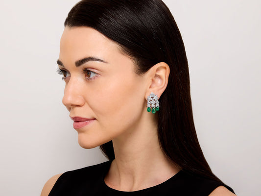 Woman wearing diamond and emerald drop earrings in white gold