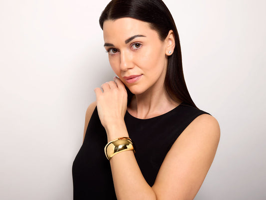 Model wearing a polished 18K yellow gold hinged cuff bracelet
