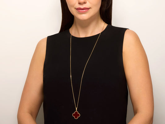 Van Cleef & Arpels 'Magic Alhambra' Carnelian Necklace in 18K Gold worn on a model, featuring a red carnelian clover pendant and long gold chain from Beladora