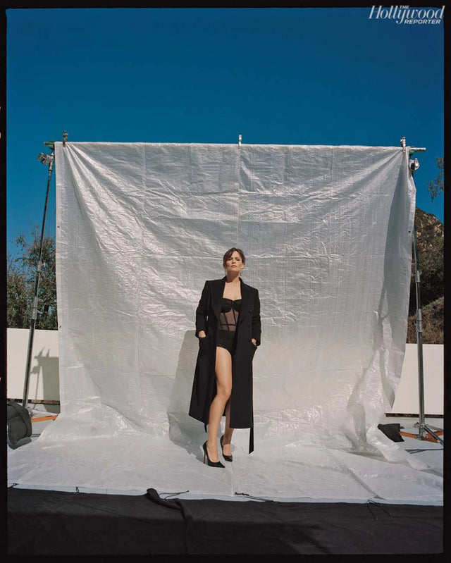 Woman in black outfit standing before a white backdrop