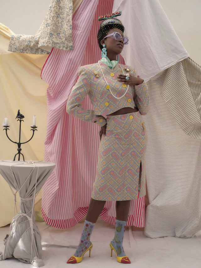 Woman in patterned two piece outfit among draped fabrics