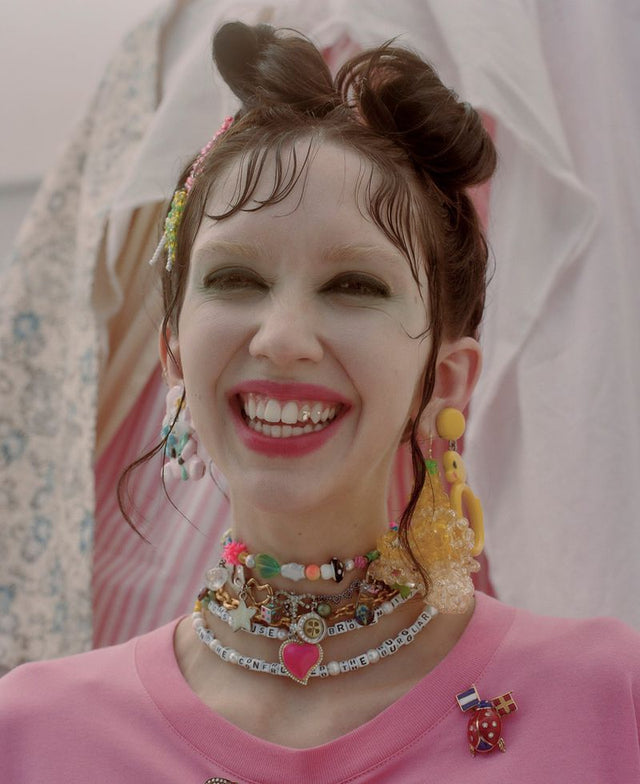 Smiling woman with colorful jewelry and pink shirt