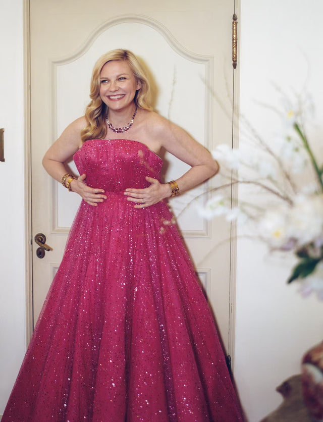 Smiling woman in a sparkling pink gown indoors