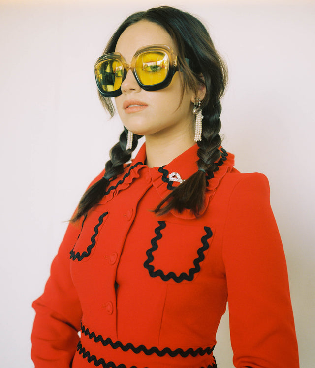 Woman in red blouse wearing oversized yellow glasses