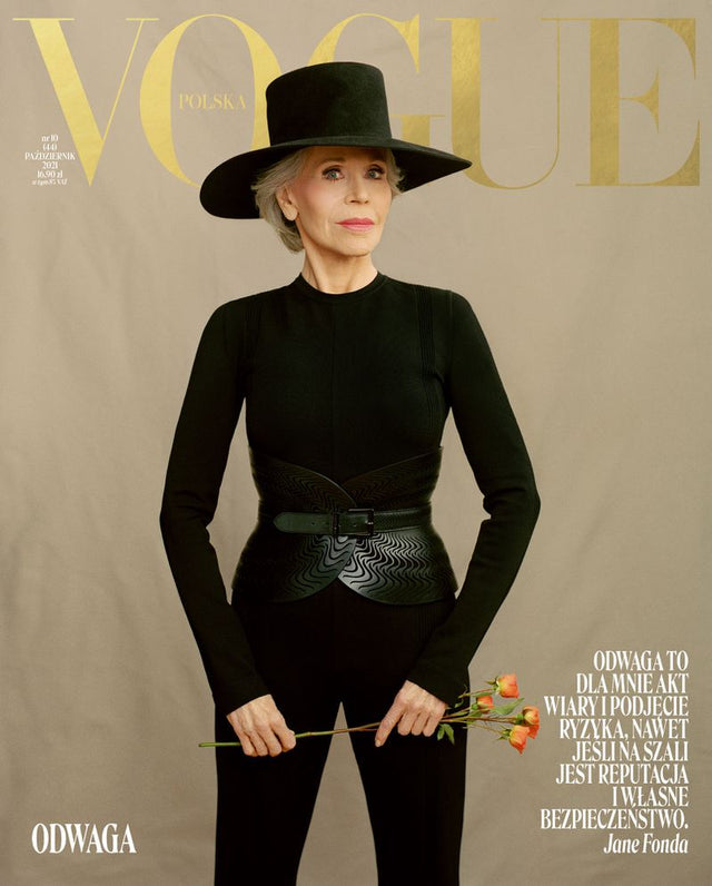 Jane Fonda posing in a black outfit while holding flowers