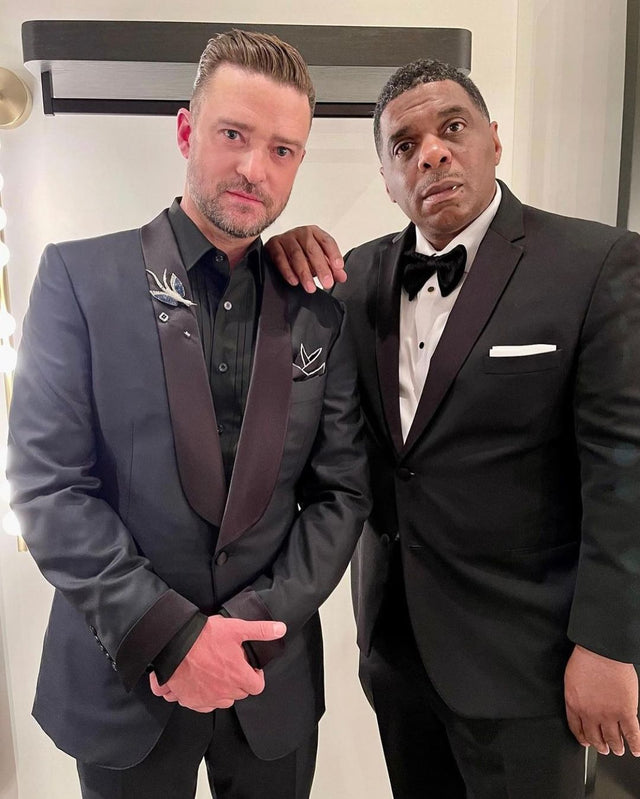 Two men in formal tuxedos posing together indoors