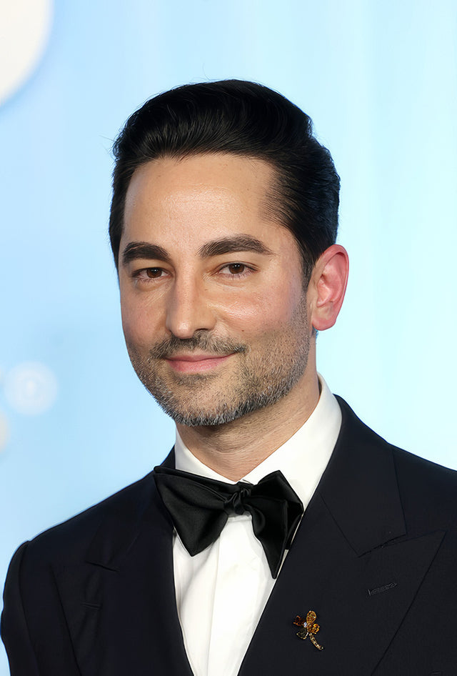 Man in black tuxedo and bow tie against blue backdrop