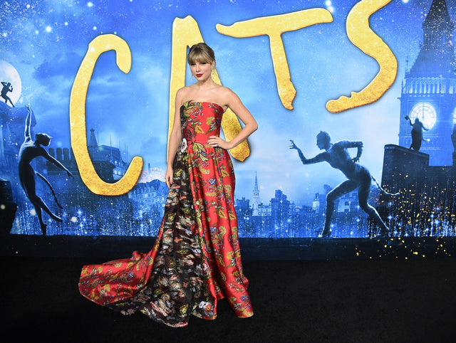 Woman in a red floral gown at a fantasy themed event backdrop