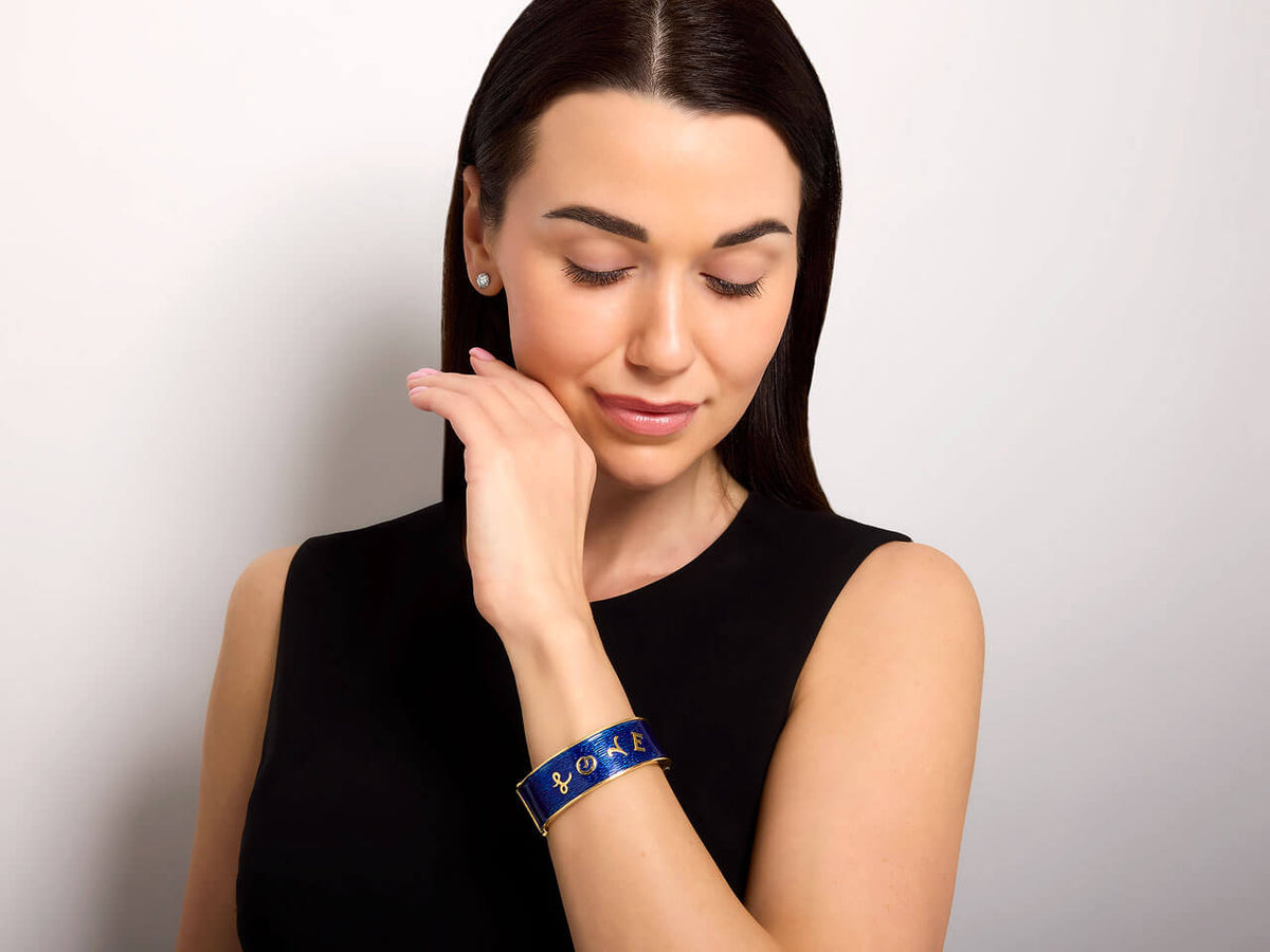 Woman wearing a blue enamel and 18K gold Love bangle