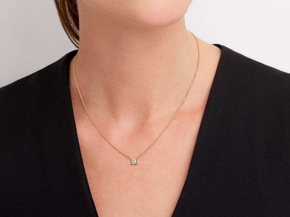 Model wearing a delicate 18K yellow gold diamond pendant