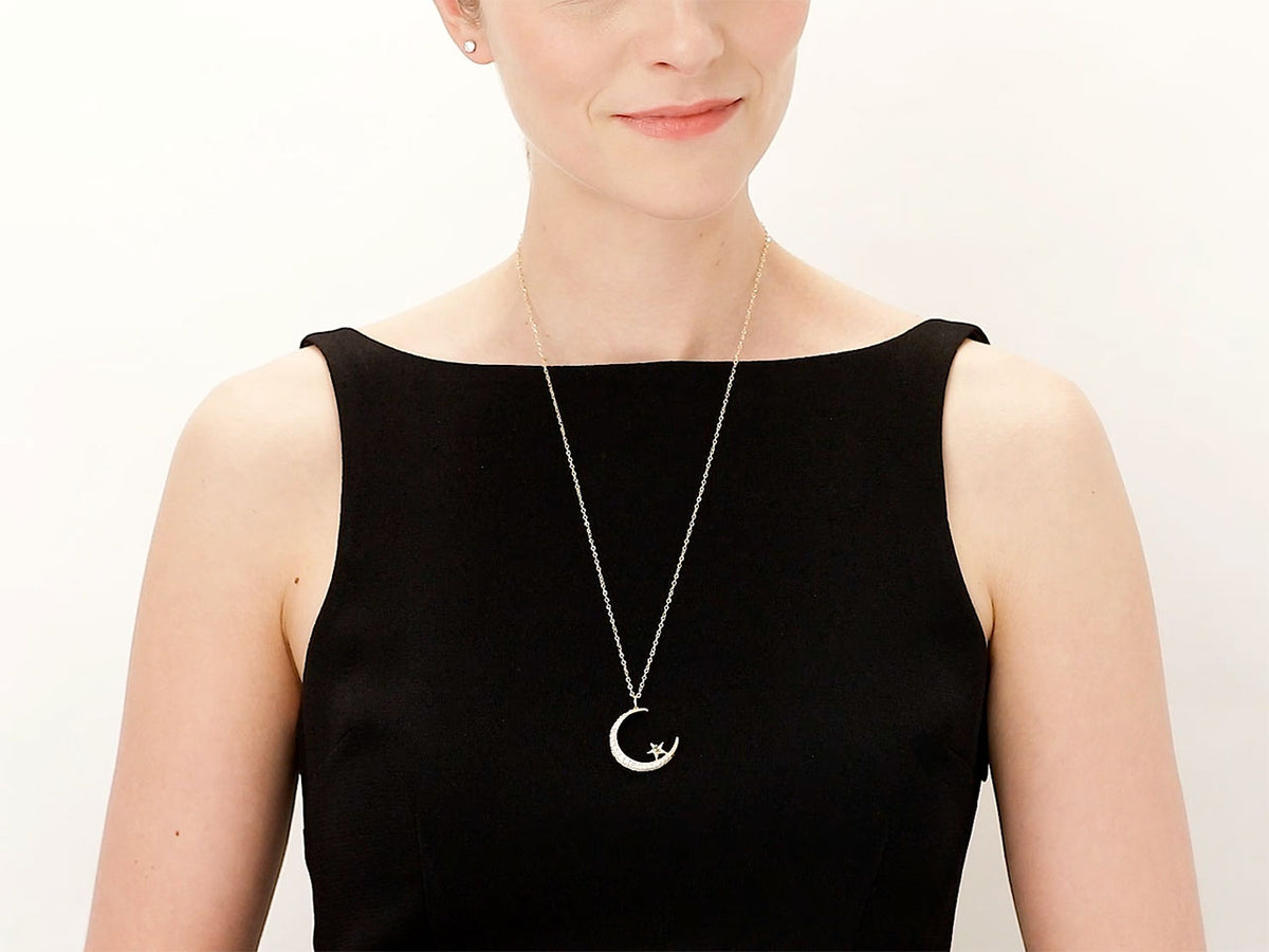 Model wearing a gold crescent pendant with diamond accents and star detail