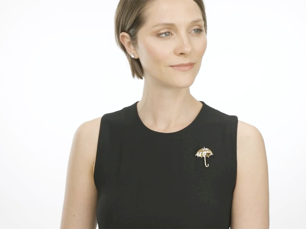 Woman wearing a black top with a gold umbrella brooch