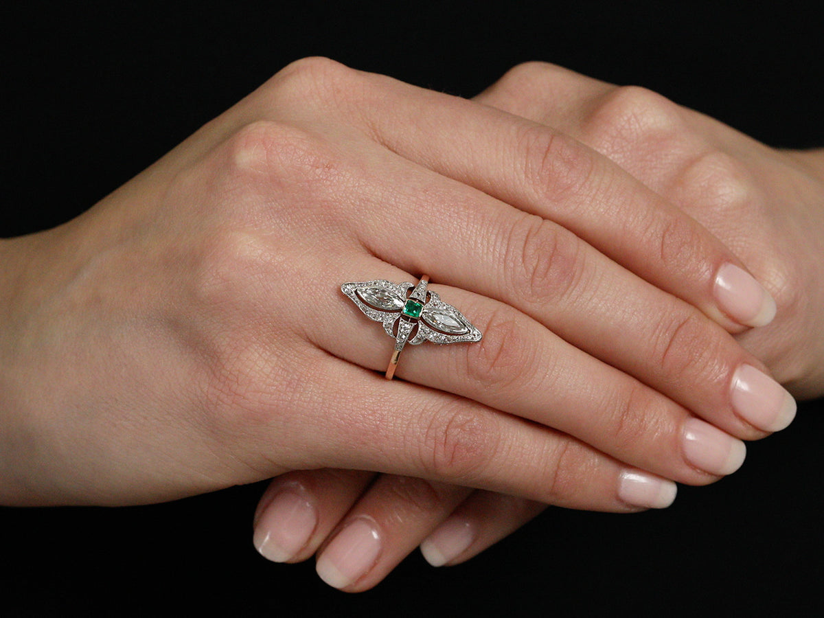Emerald and diamond navette ring worn on hand