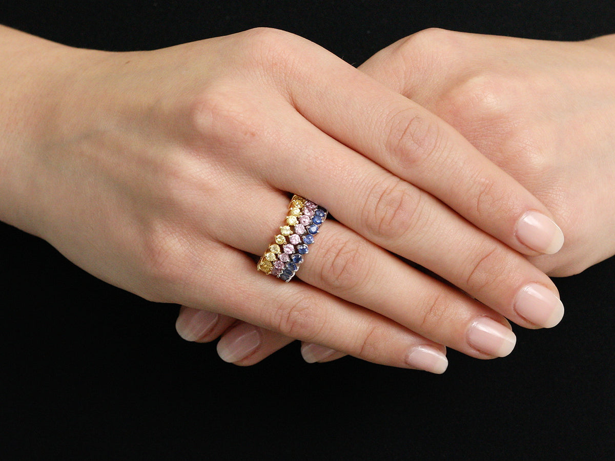 Three 18K gold sapphire bands worn on a hand