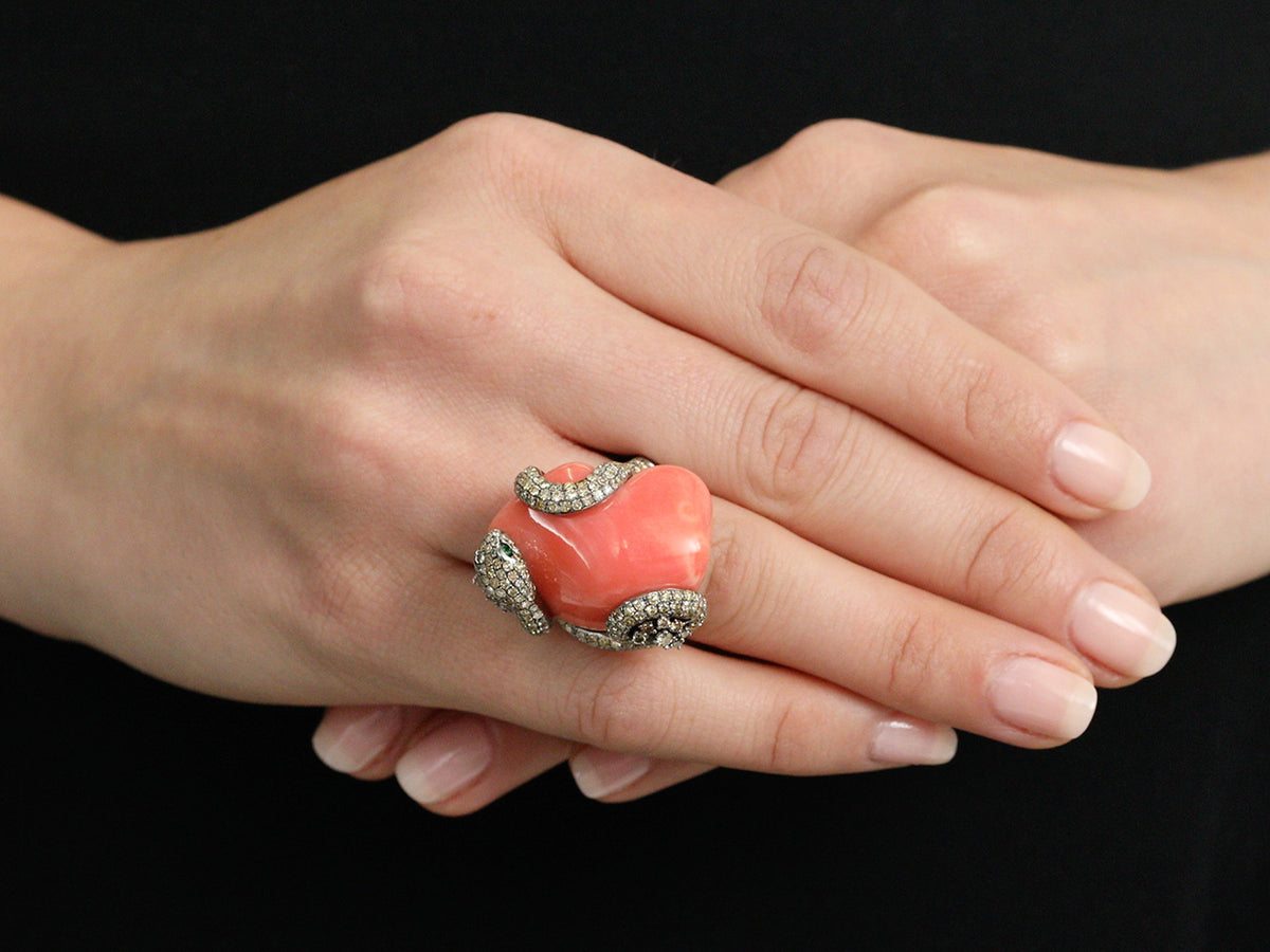 Large coral and diamond snake ring worn on a hand