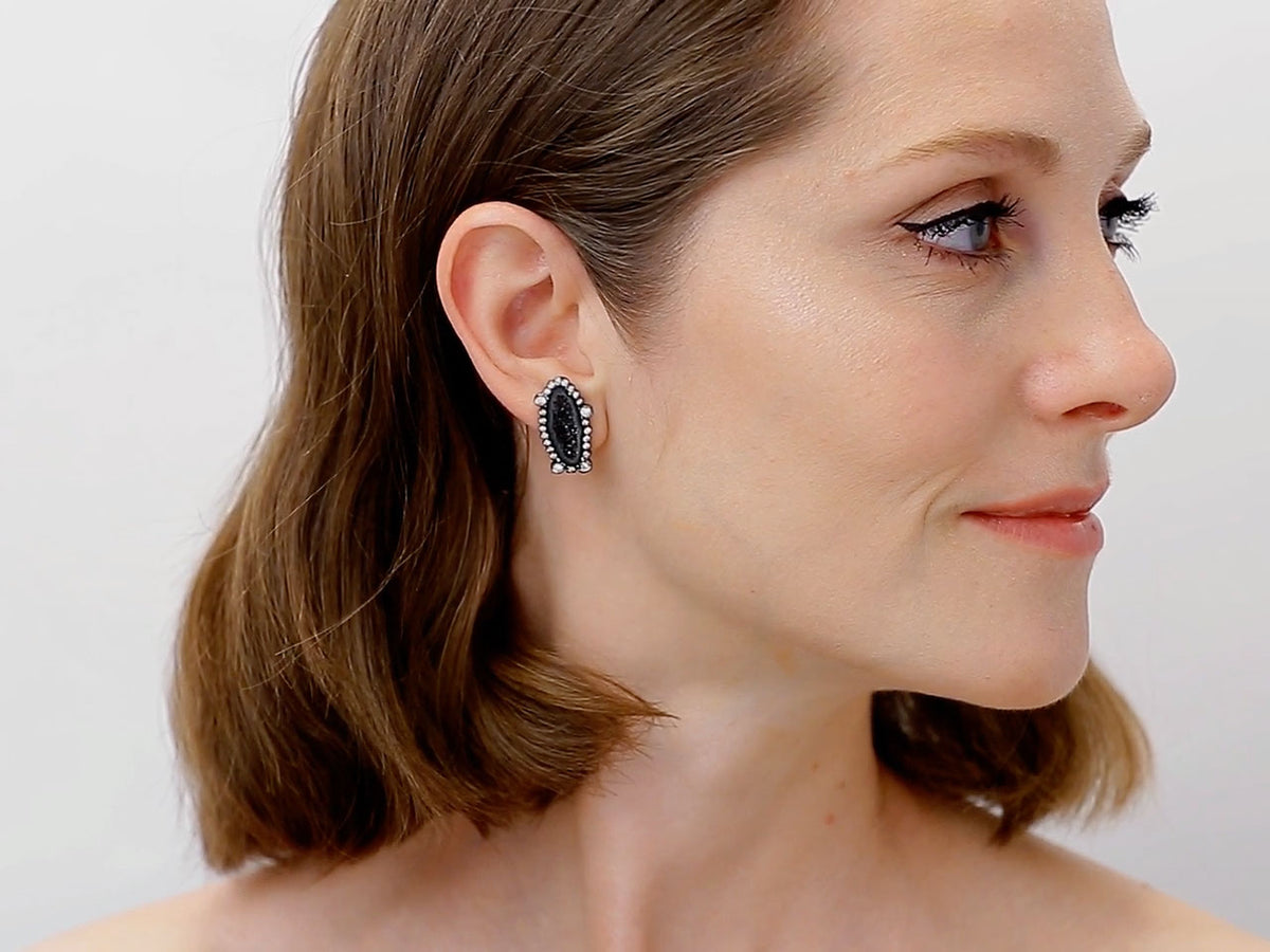 Woman wearing a black geode and diamond stud earring