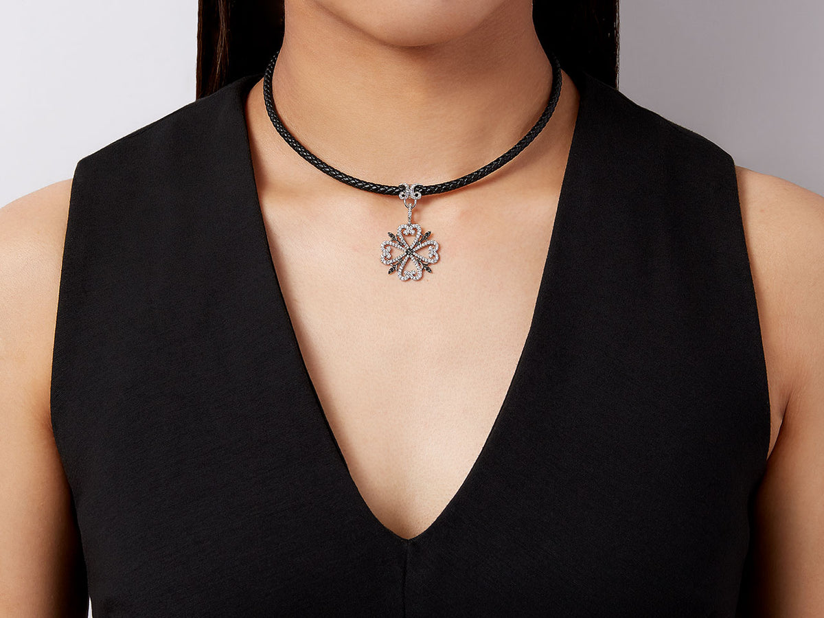 Clover pendant on a black cord necklace worn by model