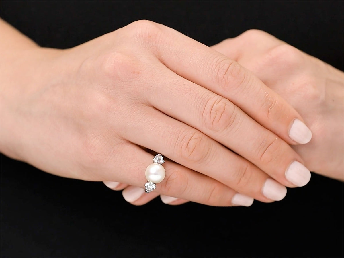 Pearl and diamond ring worn on a hand