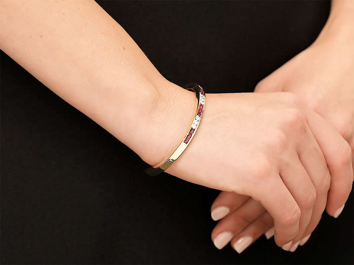 Wrist wearing an 18K gold bangle with rubies and diamonds