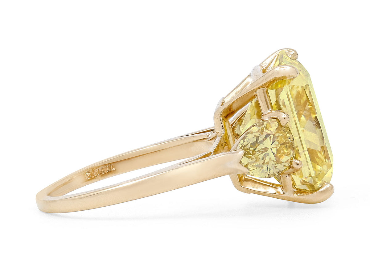 Side view of an 18k gold ring with a large yellow diamond and pear shaped side stones