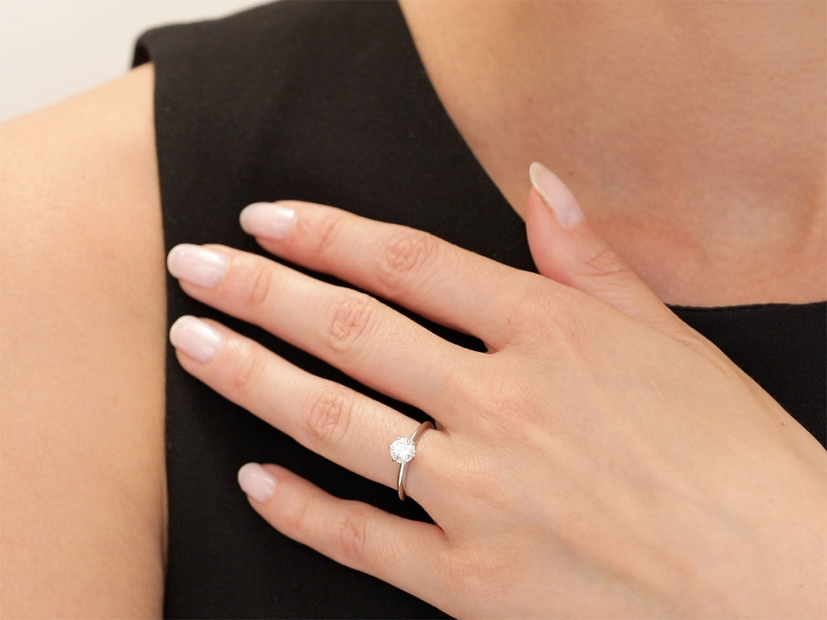 Hand wearing a six prong platinum diamond solitaire ring