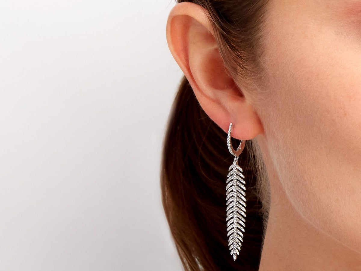 Diamond feather earring in 18K white gold worn on ear