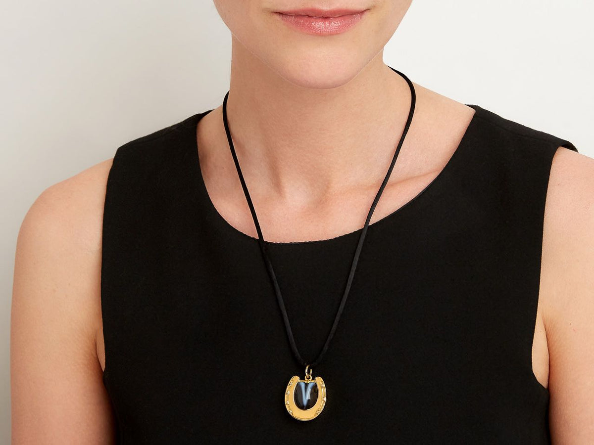 Gold horseshoe locket pendant worn on a black cord