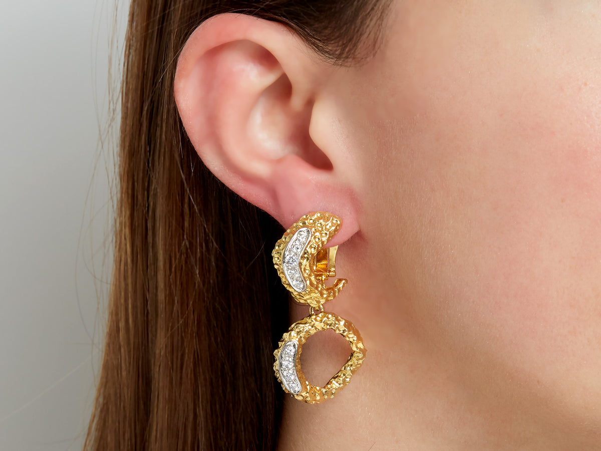 Gold and diamond drop hoop earring worn on ear