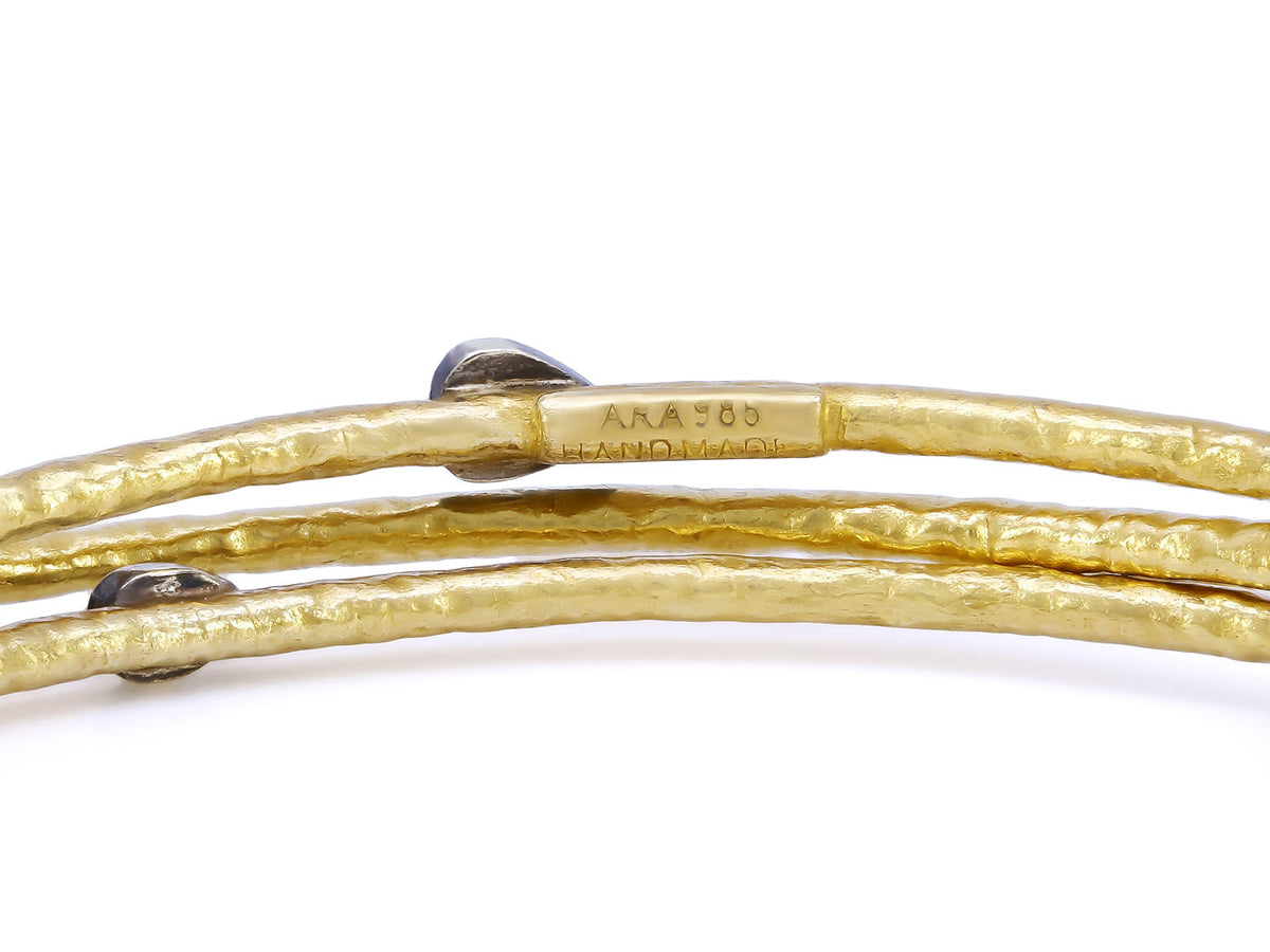 Three hammered gold bangles with silver bezels
