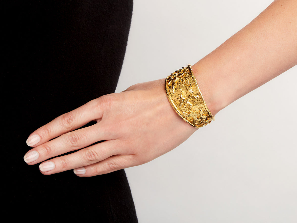 Wide hammered 22K gold cuff bracelet worn on wrist