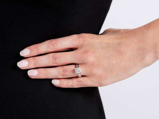 Hand wearing a platinum solitaire ring with princess cut diamond