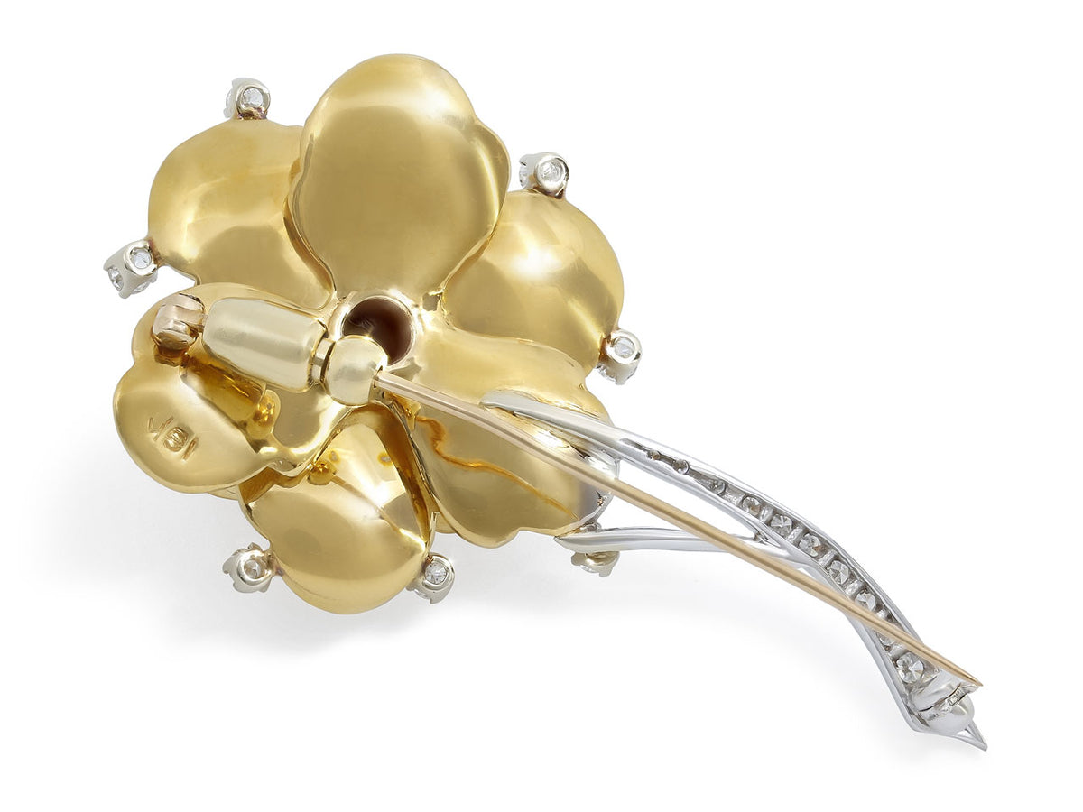 Back view of a gold flower brooch with diamond stem