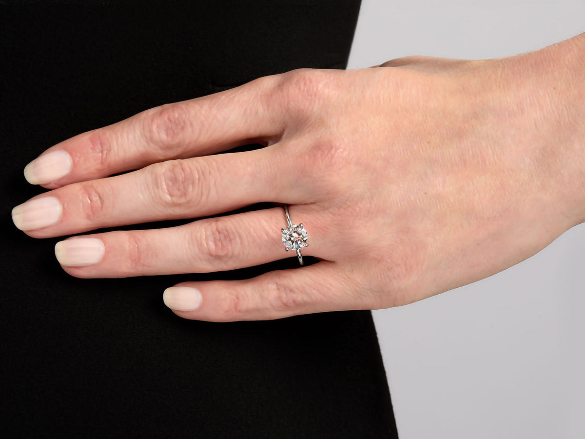 Hand wearing a round brilliant diamond ring with platinum band