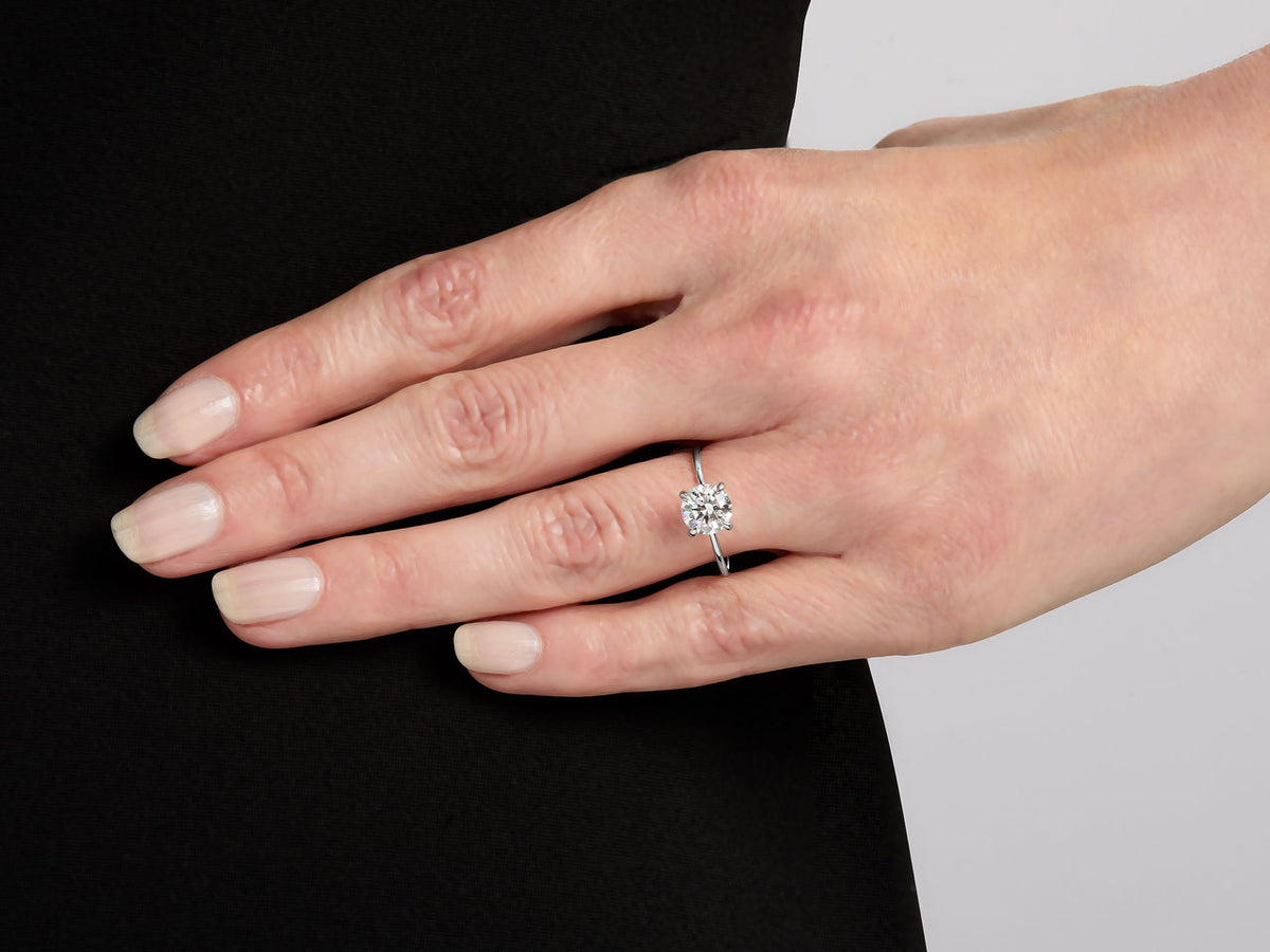 Hand wearing a platinum ring with round diamond