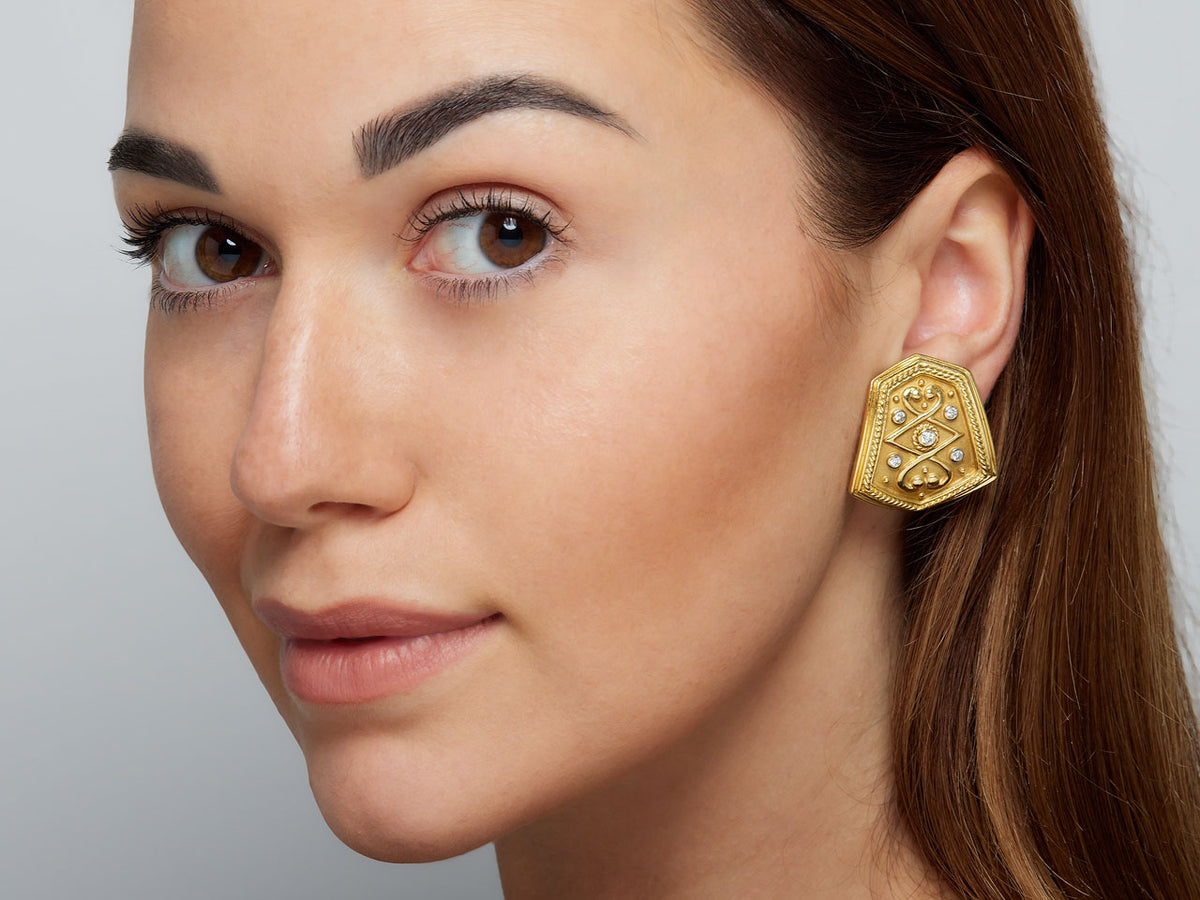 Close-up of woman wearing a gold diamond shield earring