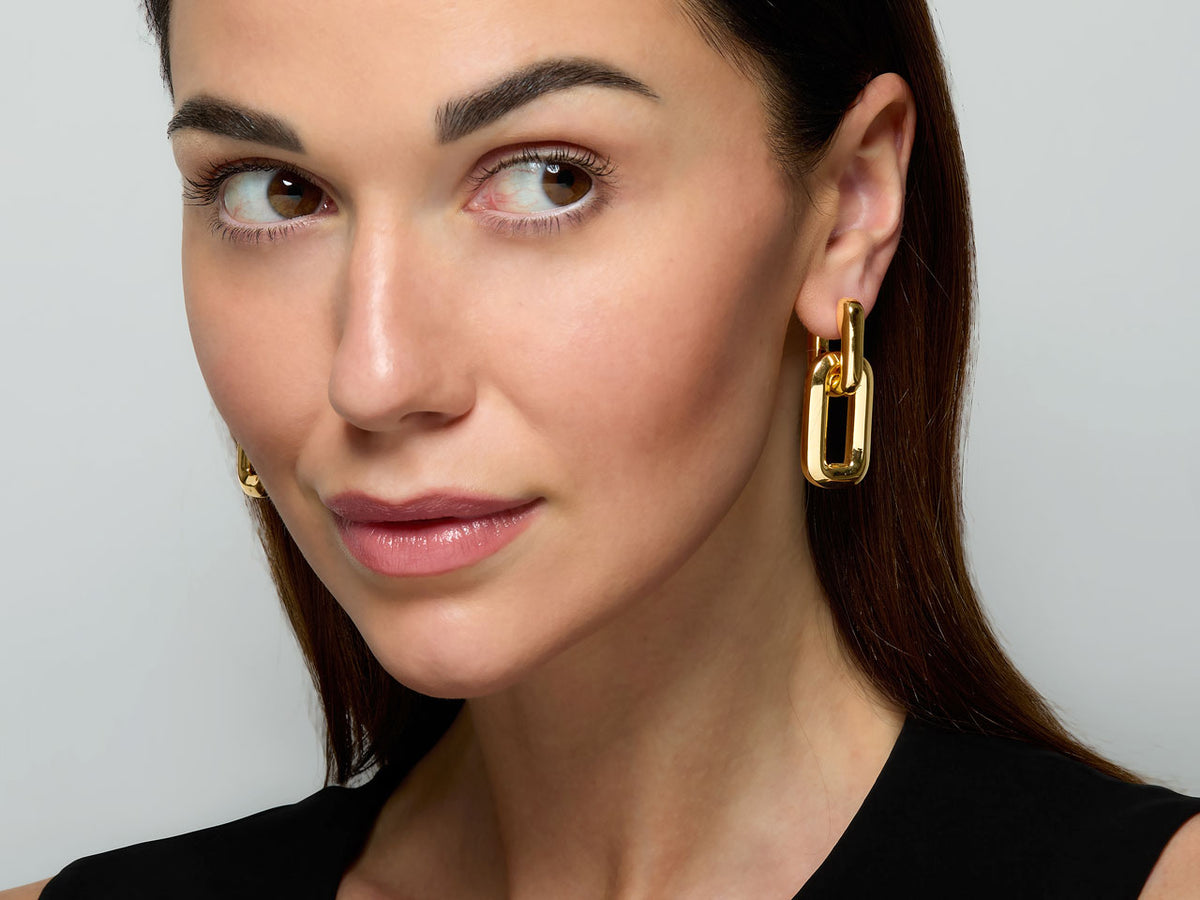 Woman wearing polished gold rectangular link earrings