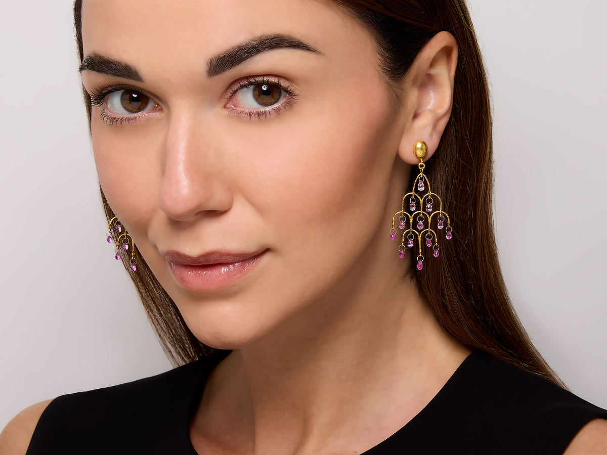 Model wearing gold chandelier earrings with pink sapphires