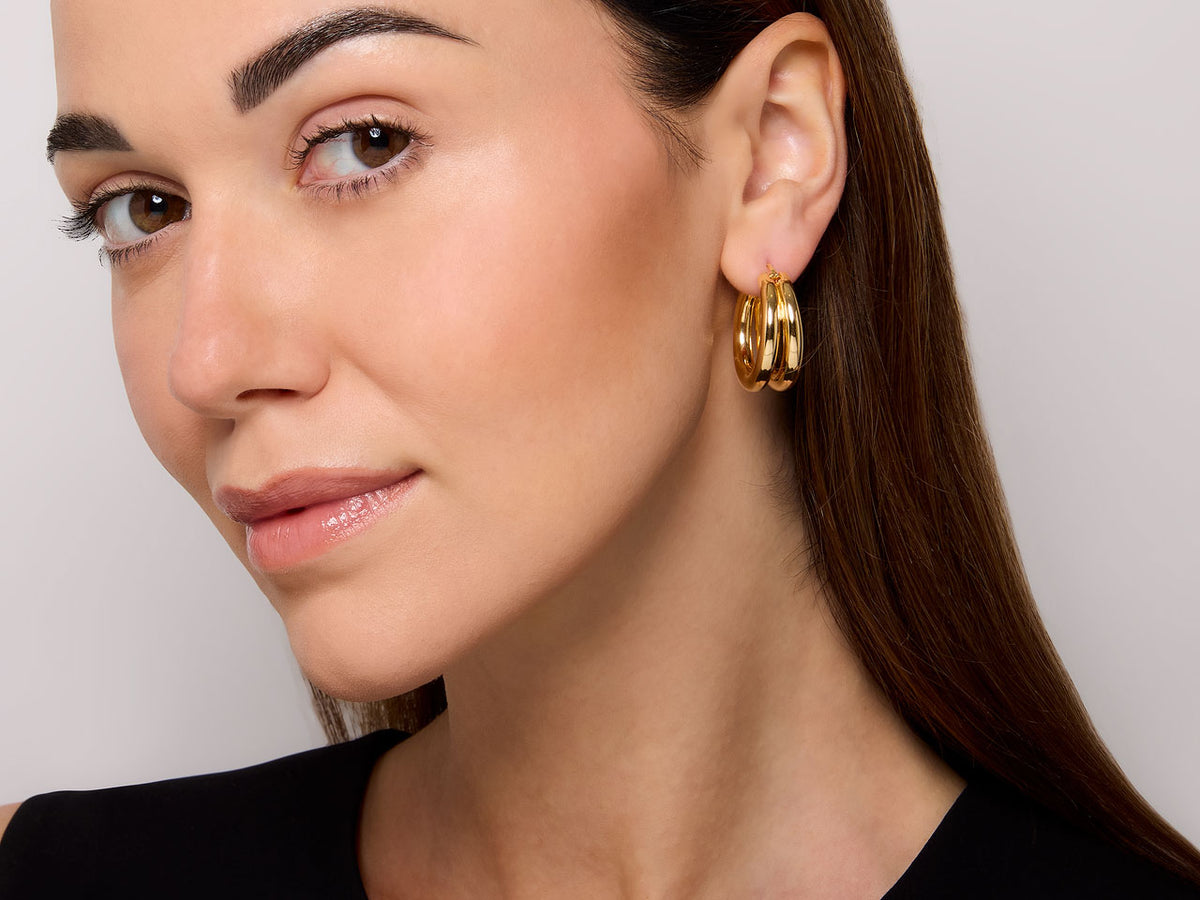 Model wearing polished 18K gold double hoop earring