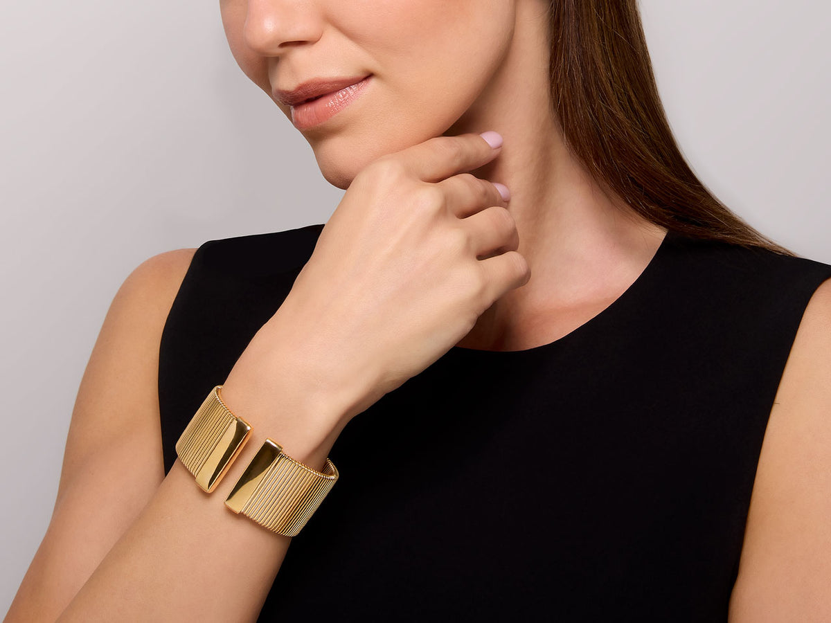 Woman wearing a wide 18K yellow gold tubogas cuff bracelet