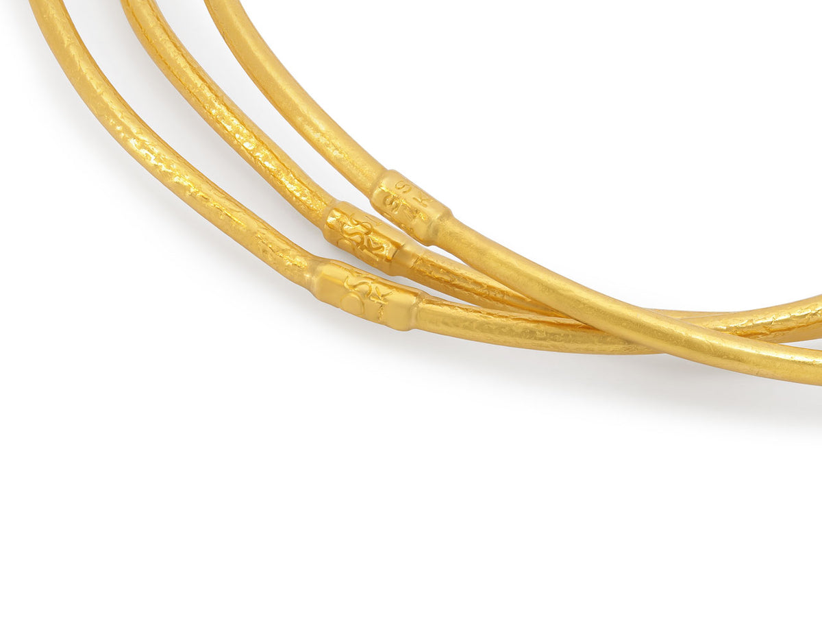 Close up of three textured 24K gold bangles