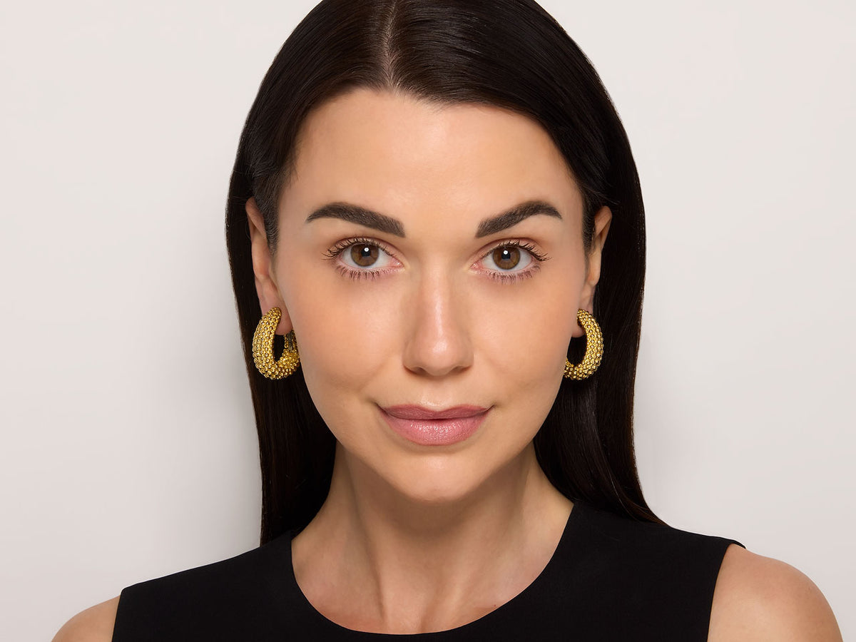 Model wearing beaded gold hoop earrings