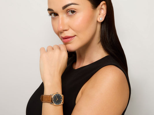 Rolex 'Cellini' Watch in 18K White and Rose Gold worn by a model, featuring a black dial, brown leather strap, and gold buckle from Beladora