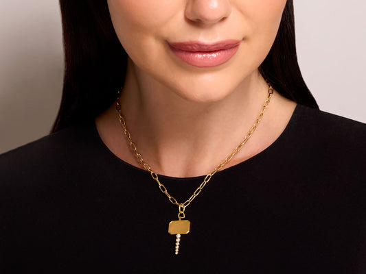 Jade Trau 'Catherine Key' Charm Pendant in 18K Gold worn on a model, showing six round diamonds on the blade and matte gold bow, by Beladora